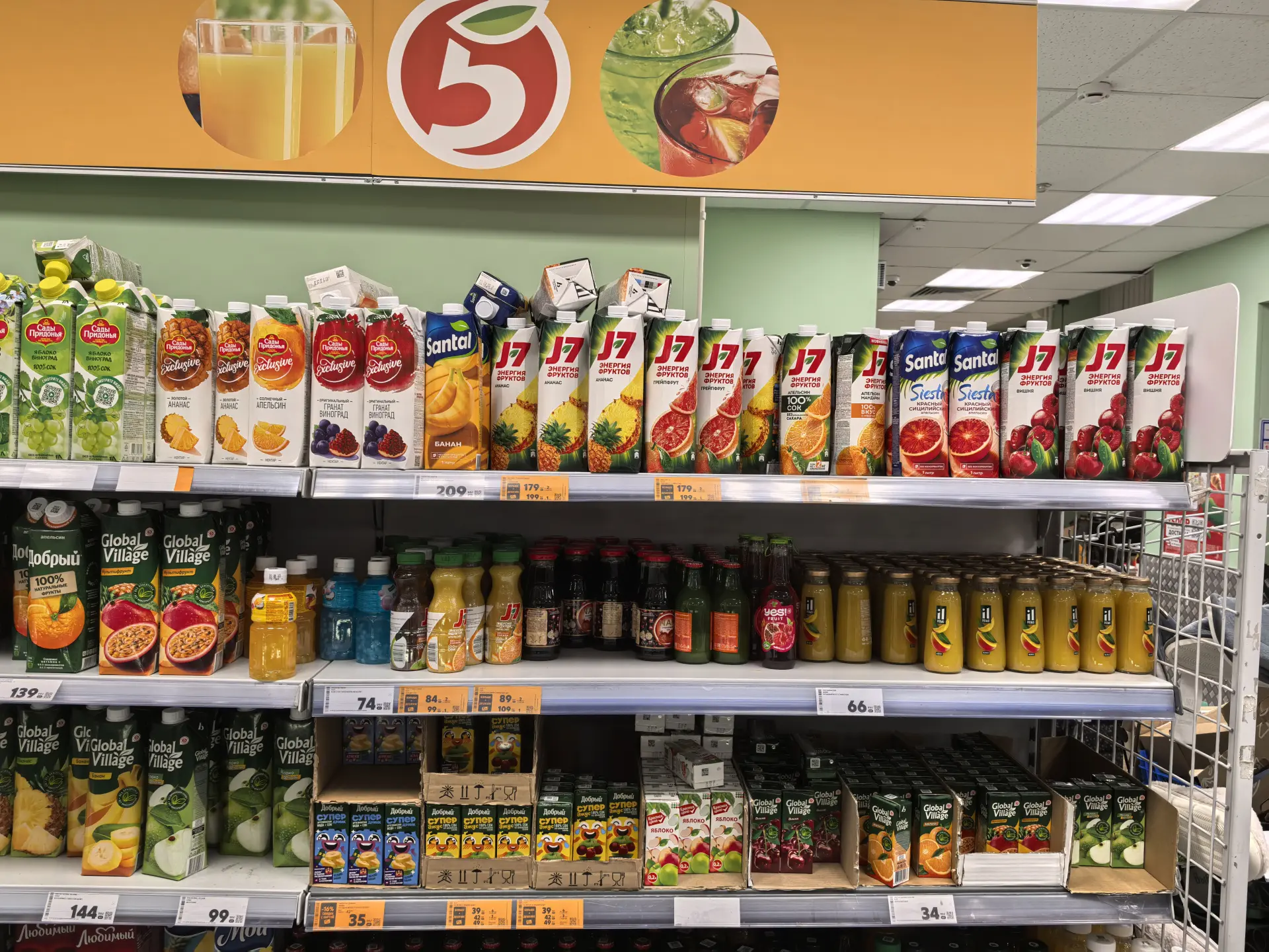 Полка в магазине с бутылками и пакетами соков, снятая на Pura 70